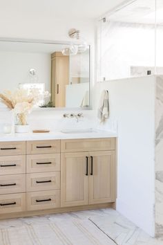 a large bathroom with marble counter tops and wooden cabinetry, along with white walls