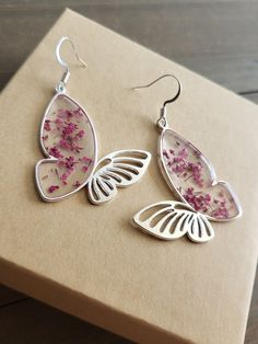 Beautifully Rose Pink flower earrings, elegant butterfly earrings with delicate, dried flowers inside. Silver butterfly earrings have silver finishing and hooks.  In earlier centuries, a gift of flowers was a meaningful gesture meant to portray the surrounding feelings involved, and show deep affection and appreciation for the receiver. It was known, Rose Pink was worn as a representation of luxury and wealth, as it was an expensive color worn by the upper class of society by privileged women of high stature. A gift of blushing rose pink flower earrings, complimented with gold, will surely bring a smile to her face. These burning pink~red floral earrings offer to be the most brilliant and unique jewelry piece in her jewelry box. Pink magenta flower earrings make a beautiful gift for brides Elegant Silver Earrings With Pressed Flowers, Silver Flower Earrings With Pressed Flowers, Silver Pressed Flowers Earrings For Gift, Silver Sterling Flower Earrings With Pressed Flowers, Silver Drop Earrings With Pressed Flowers, Silver Sterling Silver Earrings With Pressed Flowers, Silver Pressed Flower Earrings, Delicate Silver Earrings With Pressed Flowers, Sterling Silver Pressed Flower Drop Earrings