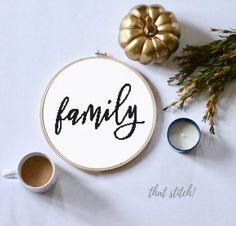 a cross stitch pattern with the word family on it next to a cup of coffee