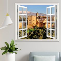 an open window with a view of a castle in the distance and trees outside it