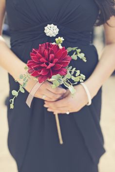 a woman in a black dress holding a red flower on her arm and the caption says,