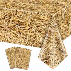 a table covered in hay next to four pieces of paper on top of each other