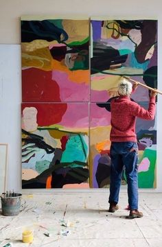 an older woman is painting on the wall