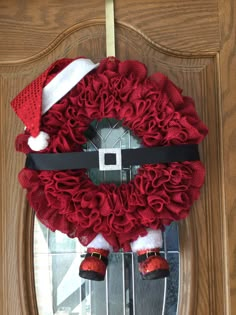 a christmas wreath with santa's hat and boots hanging on the front door handle