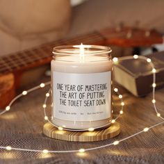 a candle sitting on top of a table next to a string of lights and a guitar