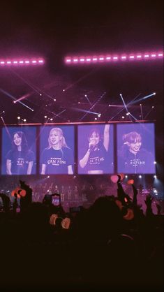 the stage is lit up with purple lights and people are waving their hands in front of them