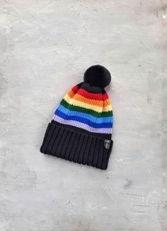 a multicolored knitted beanie hat laying on top of a white surface