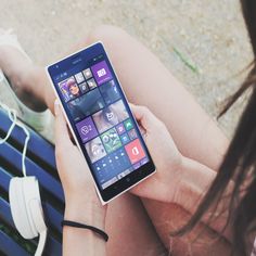 a woman sitting on a bench holding a cell phone with windows phone psd mockup