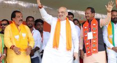 two men in orange and white are waving at the camera while others stand behind them