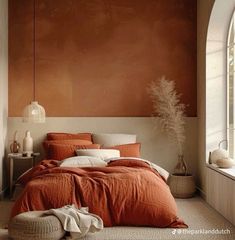 a bed with an orange comforter and pillows