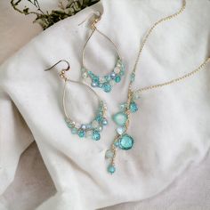 Discover our Aqua Quartz Collection - a must-have for aquamarine lovers! Immerse yourself in the tranquil allure of oceanic beauty, reminiscent of Seaglass hues. Featuring my signature Anna hoops adorned with ombre aquatic gems, available in 14k Gold-Filled or Sterling Silver. Elevate your look with our sophisticated Y-style necklace, meticulously crafted in 14k Gold-Filled (also offered in silver), adjustable from 17 to 19 inches for the perfect fit. Complete your ensemble with coordinating 1.7 Turquoise Crystal Jewelry Gift, Turquoise Crystal Jewelry For Gifts, Elegant Light Blue Crystal Necklace Gift, Elegant Light Blue Crystal Necklace For Gift, Briolette Aquamarine Necklace For Gifts, Turquoise Aquamarine Round Necklace, Turquoise Aquamarine Necklace, Round Turquoise Aquamarine Necklace, Elegant Glass Teardrop Pendant Jewelry