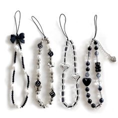 four different necklaces are lined up on a white surface with black and white beads