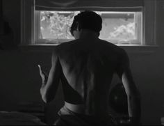 a man standing in front of a window with no shirt on