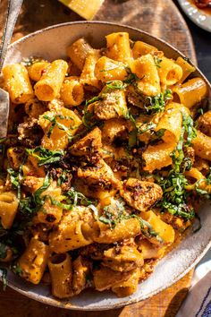 a bowl filled with pasta and meat on top of a wooden table