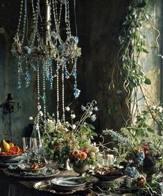 the table is set with plates, silverware and flowers in front of an ornate chandelier