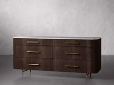 a brown and white dresser with gold handles on it's sides, against a gray wall