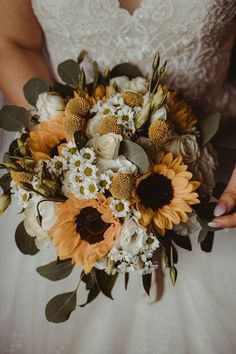 a bride holding a bouquet of sunflowers and other flowers