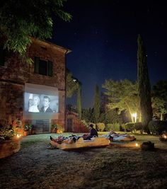 an outdoor movie is set up on the lawn in front of a house at night