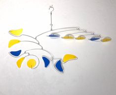 a metal wind chime with blue, yellow and white shapes