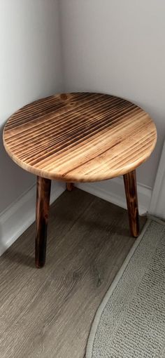 a wooden table sitting on top of a hard wood floor next to a white wall