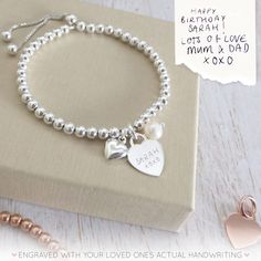 "Our beautiful range of engraved handwriting jewellery makes a beautiful dedication to a loved one, all it takes is a photo of their handwriting for our engraving team to work from. This beautiful silver bracelet combines a silver heart charm, perfect for engraving a name or a short message from a handwriting sample, alongside a beautiful pearl and a dainty silver puffed heart charm. The sterling silver heart charm measures 12mm across the front of the heart and sits centrally on a sterling silv Anniversary Engraved Sterling Silver Name Bracelet, Sterling Silver Name Bracelet With Engraving For Anniversary, White Gold Charm Bracelet For Anniversary On Mother's Day, Elegant Hand Stamped Silver Name Bracelet, Silver Hand Stamped Bracelets For Gift, Elegant Name Bracelet With Engraving For Mother's Day, Silver Name Bracelet With Engraving For Anniversary, Silver Name Bracelet With Heart Charm For Gift, Silver Name Bracelet With Heart Charm As Gift