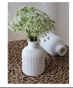 two white vases sitting on top of a woven table cloth next to each other