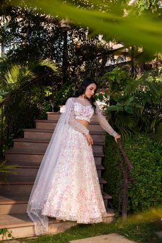 Elevate your wardrobe with this exquisite Suruchi Parakh Off-White Net Embroidered Lehenga Set. Crafted from delicate net fabric, this set features intricate handwork that adds a touch of elegance and sophistication to the entire outfit.
The off-white lehenga is paired with a matching blouse and a dupatta, creating a cohesive and harmonious look. The blouse has a classic round neckline and half sleeves, and the dupatta drapes beautifully on the body, enhancing your curves and adding a touch of g Bollywood Style White Ceremony Dress, White Gown With Resham Embroidery For Ceremony, White Dress With Zari Work For Ceremony, Floor-length Sets With Floral Embroidery For Ceremony, Floor-length Ceremony Sets With Floral Embroidery, White Gown With Zari Work For Ceremony, White Gown With Dupatta For Ceremony, White Gown With Traditional Drape For Ceremony, White Organza Dress With Zari Work