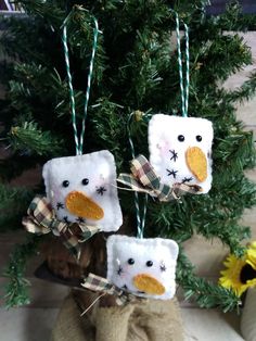 three snowman ornaments hanging from a christmas tree