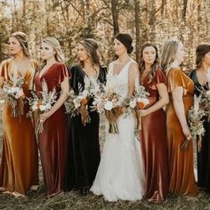 a group of women standing next to each other wearing dresses and holding bouquets in their hands