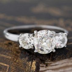 A trilogy ring with perfect proportions! The center old mine cut diamond has a beautiful, soft elongated shape, flanked by 2 old vintage round diamonds. The proportions allow the center stone to remain the star of the show, and the side diamonds complement it perfectly. The old mine cushion shows a whisper of a color - like looking at antique lace!A timeless choice. Platinum Size 8.25 & fully resizable Side stones are estimated to be H/K colors & VS2/VS1 clarities, GIA standards. Please see qual Vintage White Three Stone Diamond Ring, Vintage White Three Stone Ring, Vintage White Three-stone Ring, Vintage Three Stone Round Cut Diamond Ring, Heirloom White Three Stone Diamond Ring, Vintage Three Stone Diamond Ring, Modern Mens Rings, Diamond Trilogy Ring, Art Jewelry Earrings