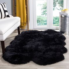 a living room with a large black rug on the floor next to a white chair