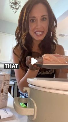 a woman holding a plate with meat on it in front of a stove top oven