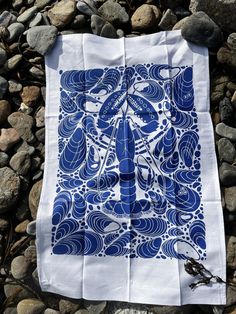 a blue and white cloth with an image of a dragonfly on it sitting on some rocks