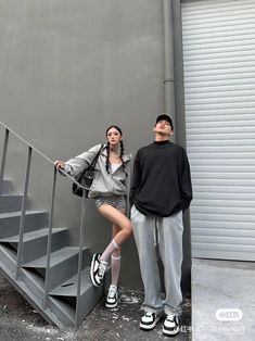 a man and woman standing next to each other in front of a metal stair case