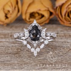 a black and white diamond ring on top of a wooden table with roses in the background