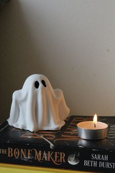 a candle that is sitting on top of a book with a ghost figure next to it