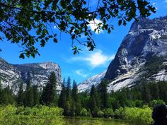 a person is sitting on a bench looking at the mountains and trees in the distance