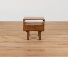 a small wooden table sitting on top of a hard wood floor next to a white wall