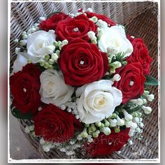 a bouquet of red and white flowers sitting on top of a wicker basket