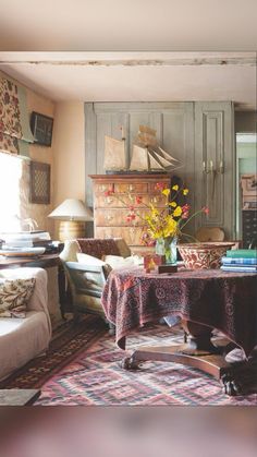 a living room filled with furniture and a table covered in a purple cloth next to a fire place