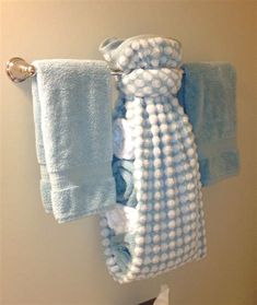 a towel hanging on the wall next to two folded towels and a soap dispenser