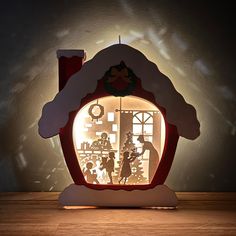 a lit up house with people in it on a wooden table next to a wall