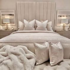 a bed with white pillows and blankets on it in a bedroom next to two nightstands