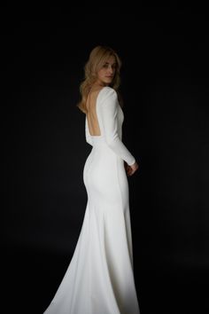 a woman in a white dress is standing with her back turned to the camera and she has