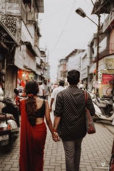 a man and woman walking down a street holding hands