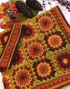 two crocheted placemats sitting on top of a table next to pine cones