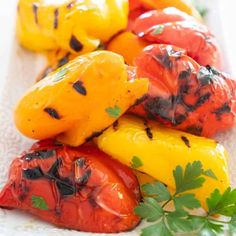 grilled peppers on a white plate with parsley garnished in red and yellow