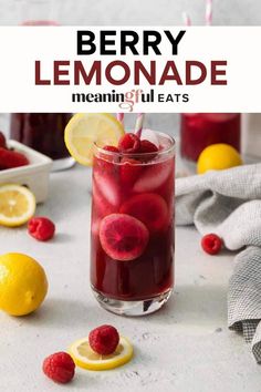 a glass filled with raspberry lemonade next to sliced lemons