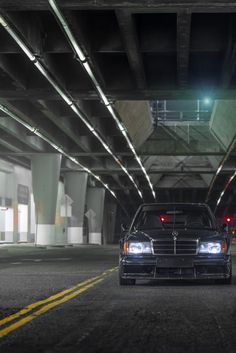 a black car parked in an underground parking garage with its lights on and it's door open