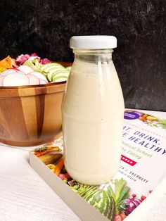 a bottle of milk sitting on top of a book next to a bowl of food